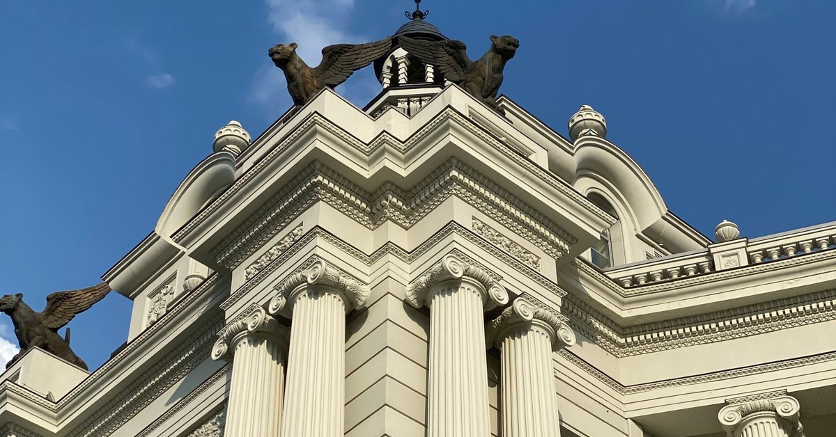 Neoclassical courthouse-style building with white columns against a blue sky