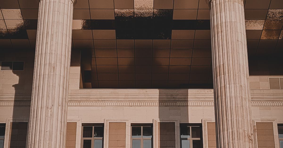 Tall stone columns at the entrance of a courthouse in warm late-afternoon light